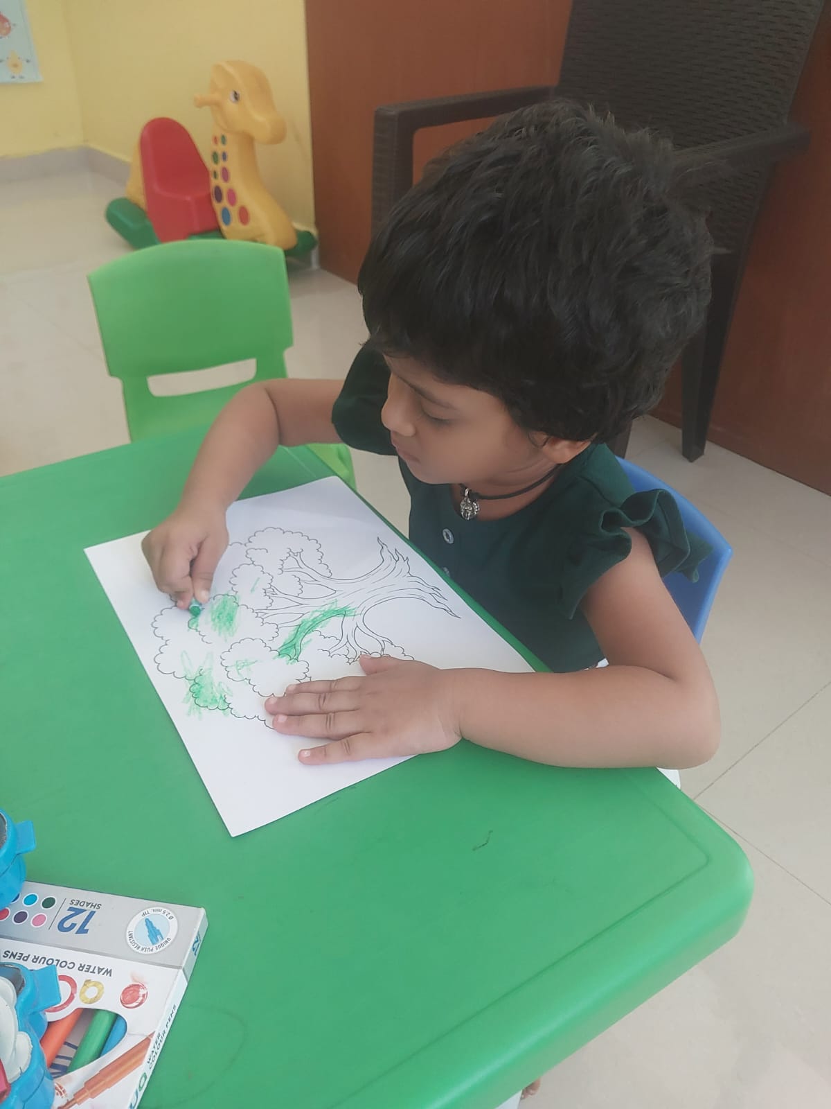 Child colouring a tree with water colour pens