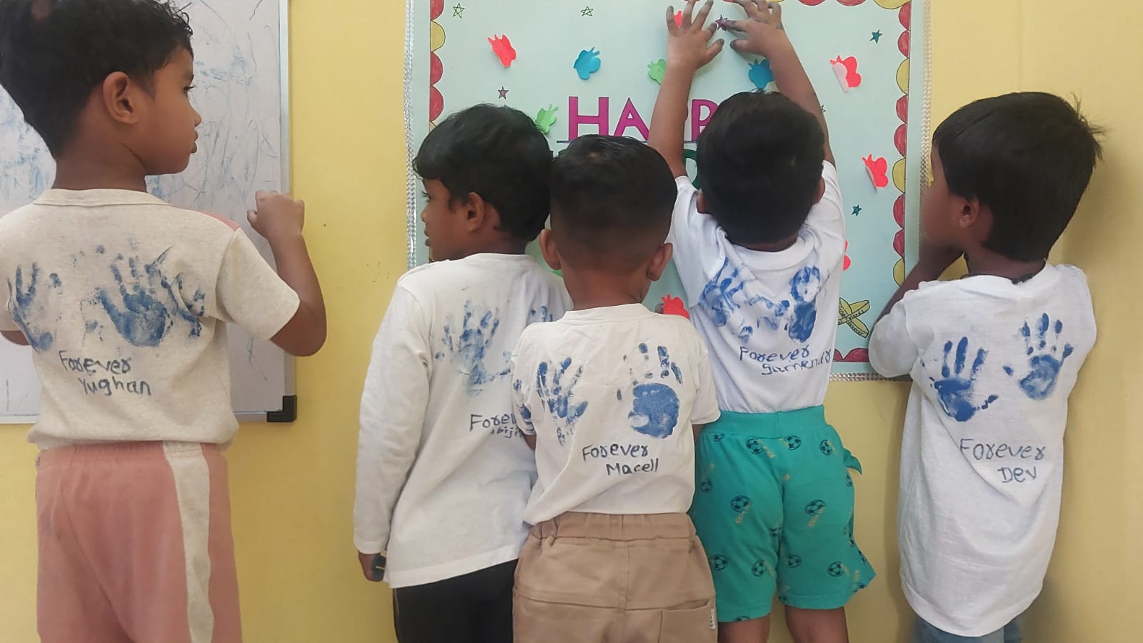Children showing off hand-print painted t-shirts in art activity