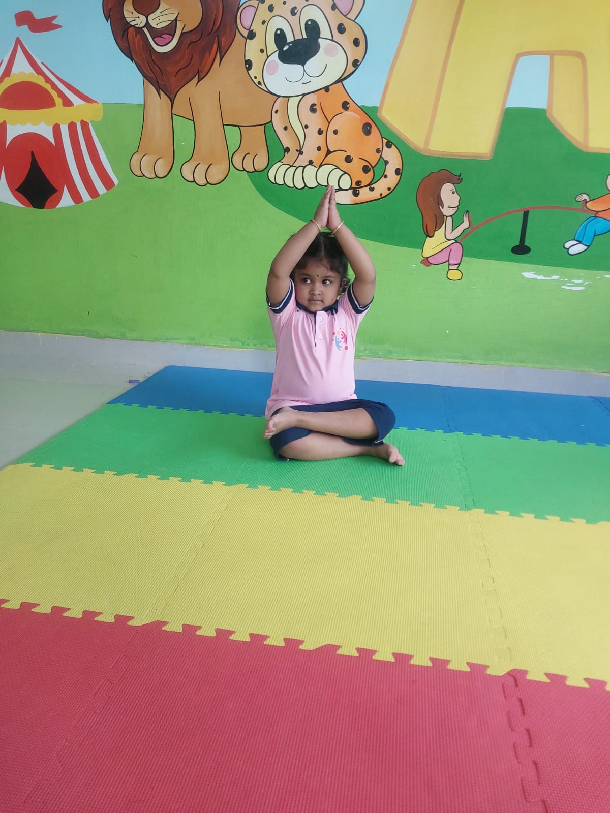 Child performing yoga lotus pose on a colourful foam mat