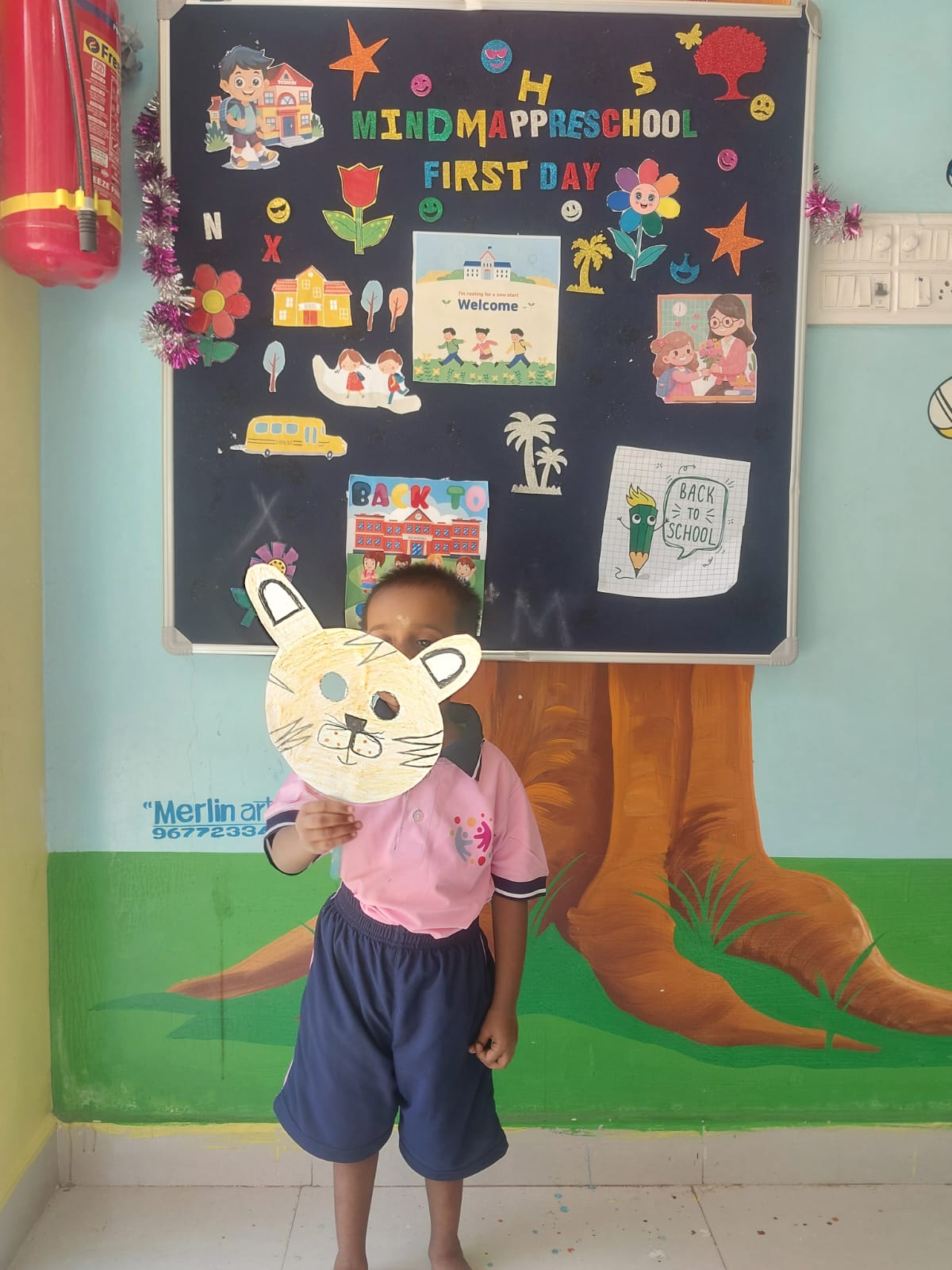 Child holding a handmade cat mask during role play activity